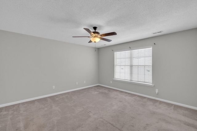 carpeted empty room featuring a textured ceiling, a ceiling fan, visible vents, and baseboards