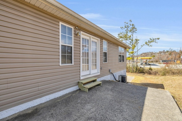 view of home's exterior with entry steps, central AC unit, and a patio area