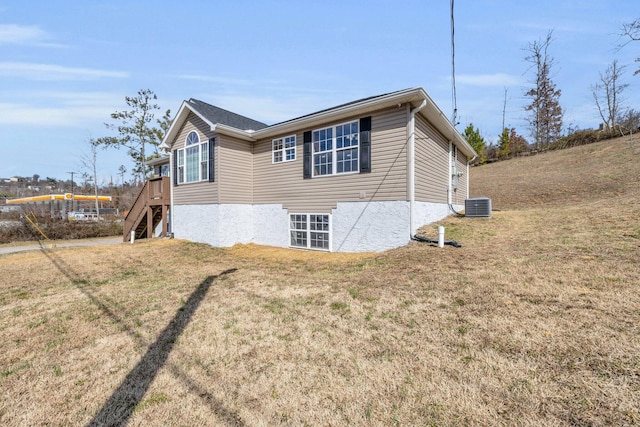 view of side of property with stairs, central AC unit, and a yard