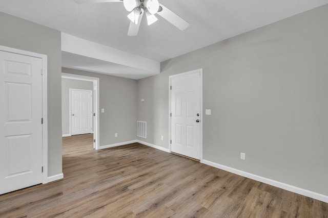 unfurnished room featuring baseboards, visible vents, ceiling fan, and wood finished floors