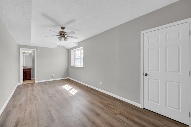 unfurnished bedroom with a textured ceiling, wood finished floors, and baseboards