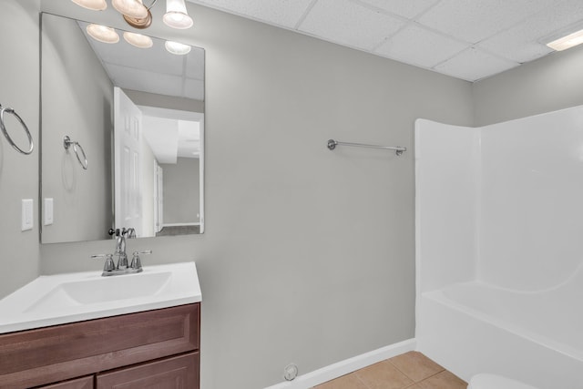 bathroom featuring a paneled ceiling, vanity, baseboards, and tile patterned floors