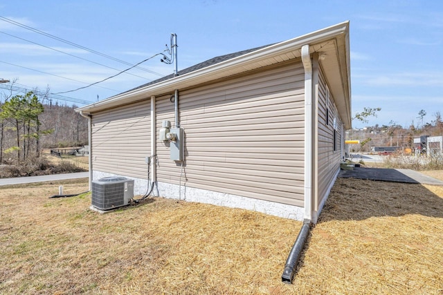 view of side of home featuring cooling unit and a yard