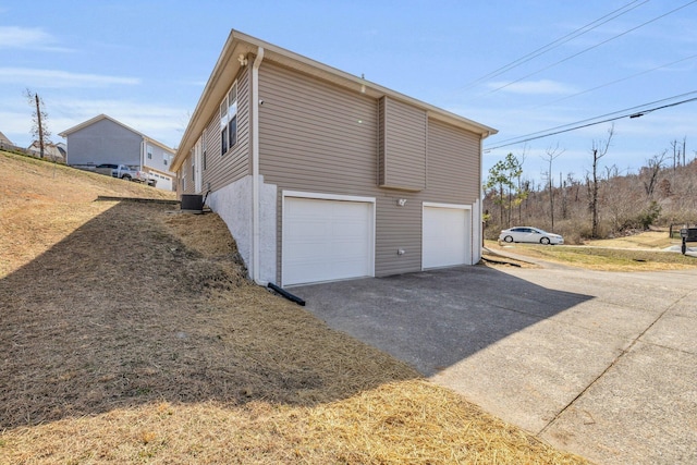 garage featuring driveway and central AC unit