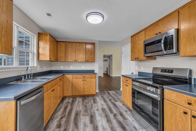 8115 Standifer Gap Rd, Chattanooga, TN 37421 - kitchen with visible vents, dark countertops, a sink, stainless steel appliances, and light wood-style flooring