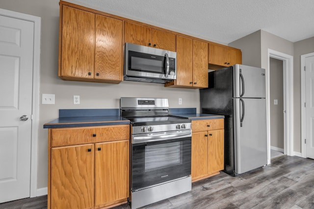 8115 Standifer Gap Rd, Chattanooga, TN 37421 - kitchen with dark countertops, a textured ceiling, brown cabinetry, stainless steel appliances, and dark wood-type flooring