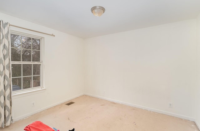 spare room with carpet flooring, visible vents, and baseboards