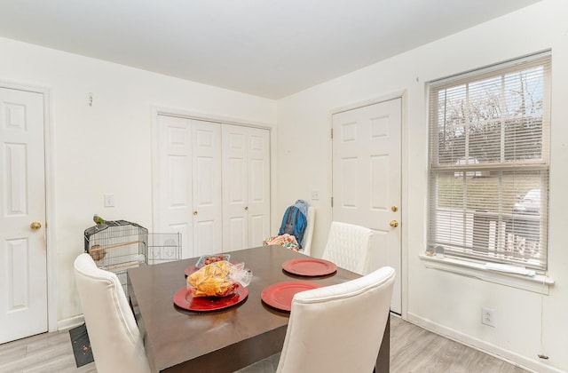 dining space with light wood-style flooring and baseboards