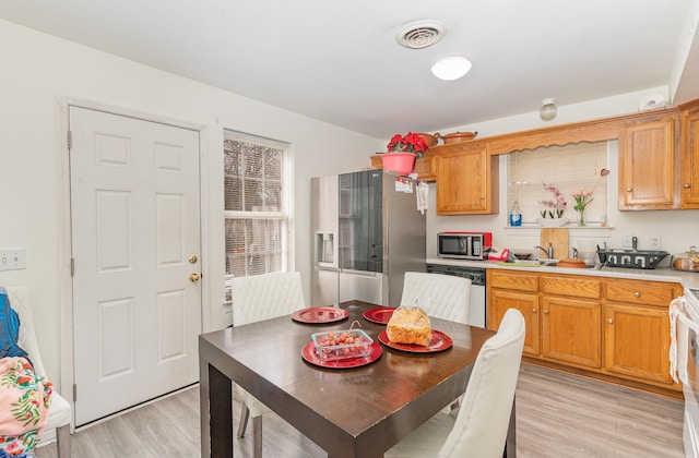 kitchen featuring light countertops, light wood-type flooring, stainless steel microwave, and dishwashing machine