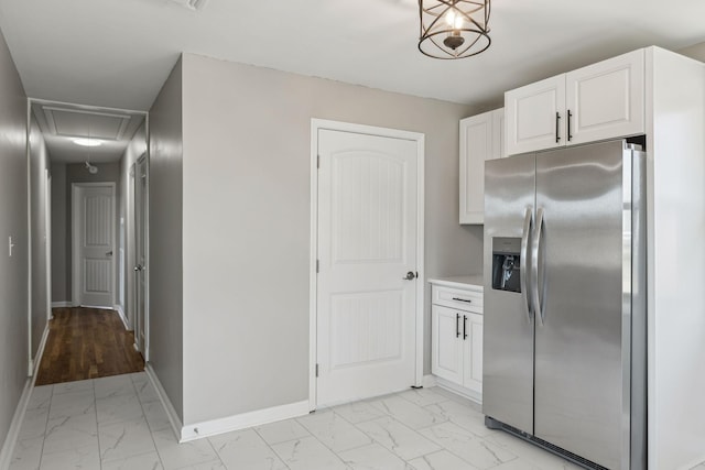 kitchen featuring baseboards, white cabinets, stainless steel fridge with ice dispenser, marble finish floor, and light countertops