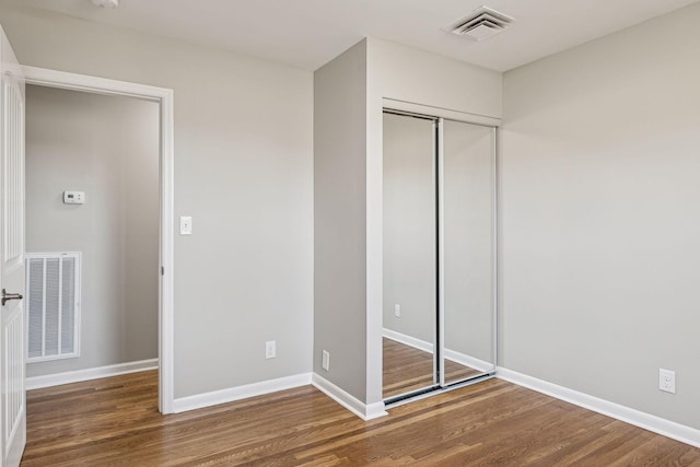 unfurnished bedroom with wood finished floors, visible vents, and baseboards