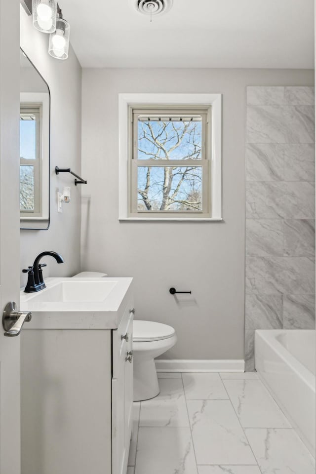 full bathroom featuring marble finish floor, a healthy amount of sunlight, toilet, and baseboards