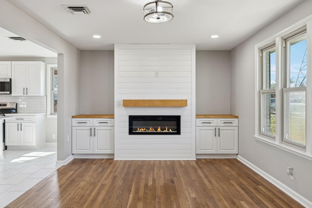 unfurnished living room featuring recessed lighting, visible vents, baseboards, and wood finished floors