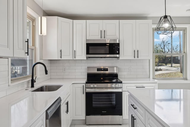 kitchen featuring stainless steel appliances, white cabinetry, a sink, and backsplash