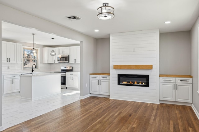 kitchen featuring stainless steel appliances, light wood-type flooring, white cabinetry, and backsplash