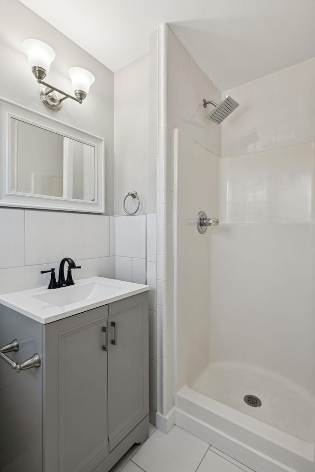 full bath featuring a stall shower, vanity, tile walls, and tile patterned floors