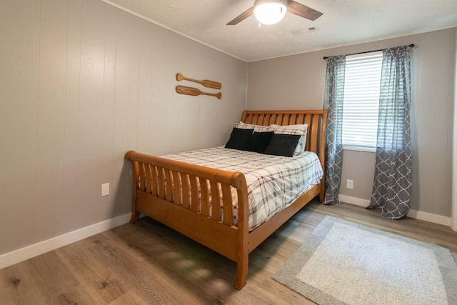 bedroom with visible vents, ceiling fan, a textured ceiling, wood finished floors, and baseboards