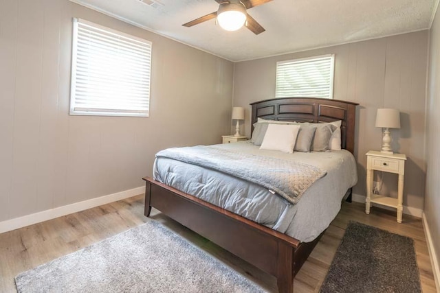 bedroom with a ceiling fan, baseboards, and wood finished floors