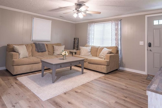 living room with baseboards, light wood-style flooring, ceiling fan, ornamental molding, and a textured ceiling