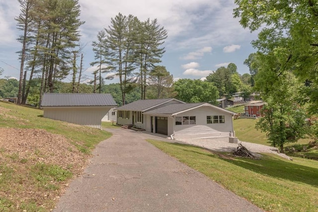 single story home featuring aphalt driveway, a front lawn, and an attached garage