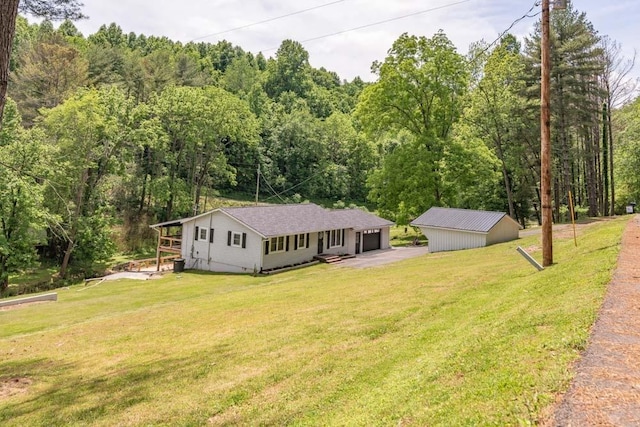 view of front of house with a front lawn, a wooded view, and an outdoor structure