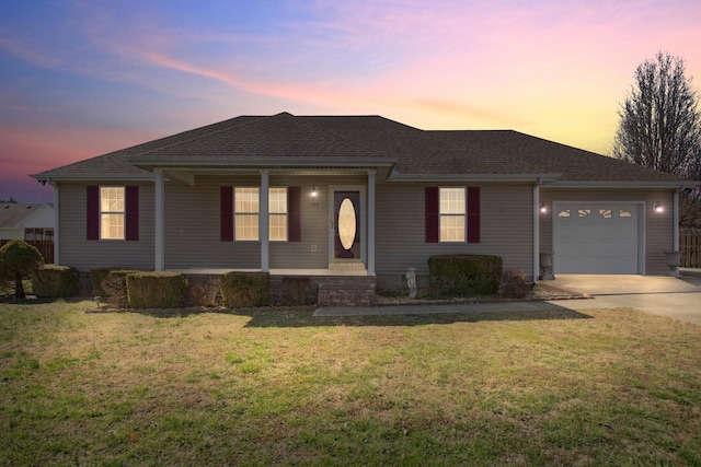 ranch-style home featuring an attached garage, a shingled roof, concrete driveway, and a yard