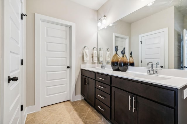 bathroom featuring double vanity, tile patterned flooring, a sink, and baseboards