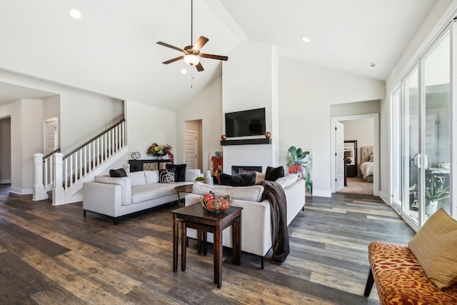 living area featuring dark wood finished floors, a ceiling fan, stairway, a fireplace, and high vaulted ceiling