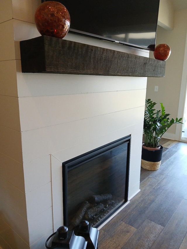 interior details featuring a glass covered fireplace, baseboards, and wood finished floors