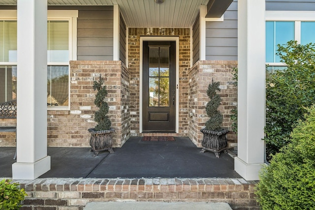 property entrance with brick siding and a porch