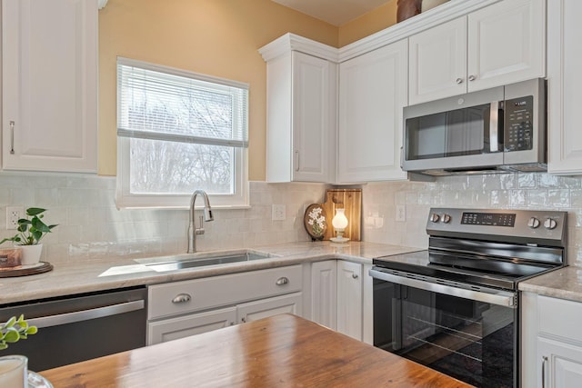 kitchen featuring stainless steel appliances, tasteful backsplash, light countertops, white cabinets, and a sink