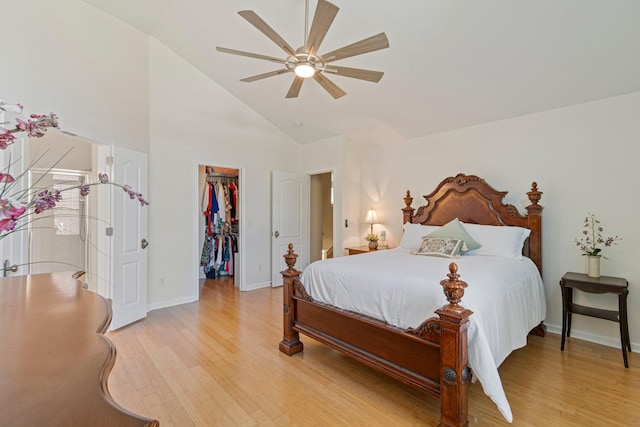 bedroom with ceiling fan, baseboards, a closet, light wood finished floors, and a walk in closet