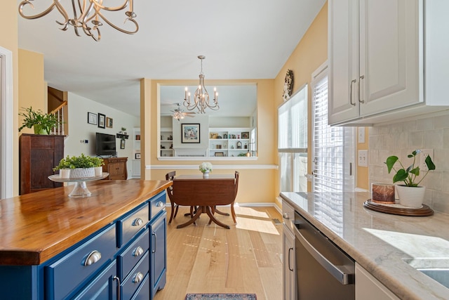 kitchen featuring a chandelier, blue cabinets, butcher block counters, backsplash, and dishwasher