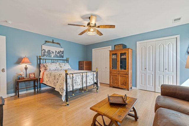 bedroom featuring light wood-style flooring, visible vents, baseboards, and multiple closets