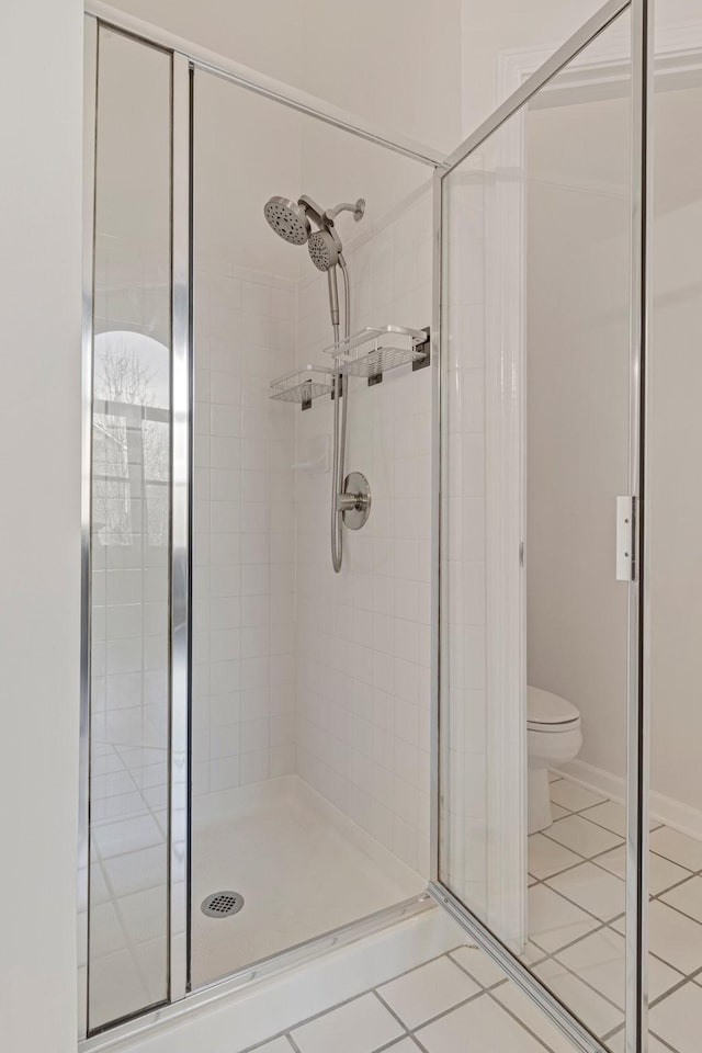 full bathroom with a stall shower, tile patterned flooring, and toilet