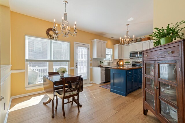 kitchen with stainless steel appliances, light wood-style flooring, an inviting chandelier, white cabinets, and blue cabinets