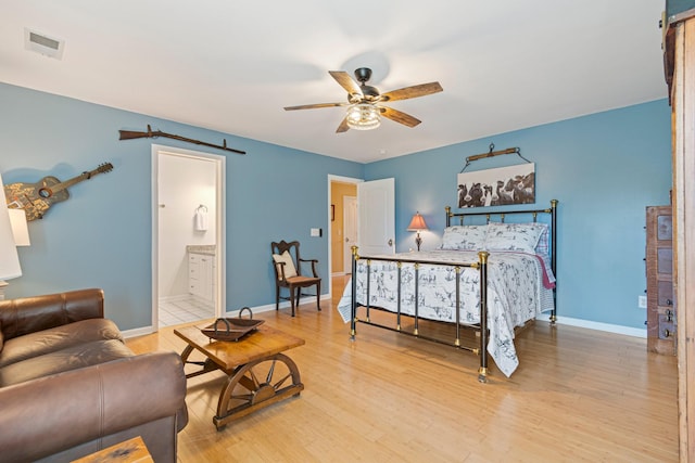 bedroom with baseboards, a barn door, visible vents, and wood finished floors