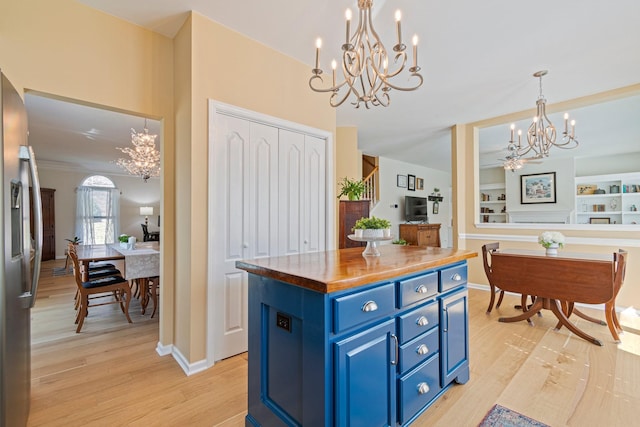 kitchen with blue cabinets, an inviting chandelier, light wood-style flooring, and stainless steel fridge with ice dispenser