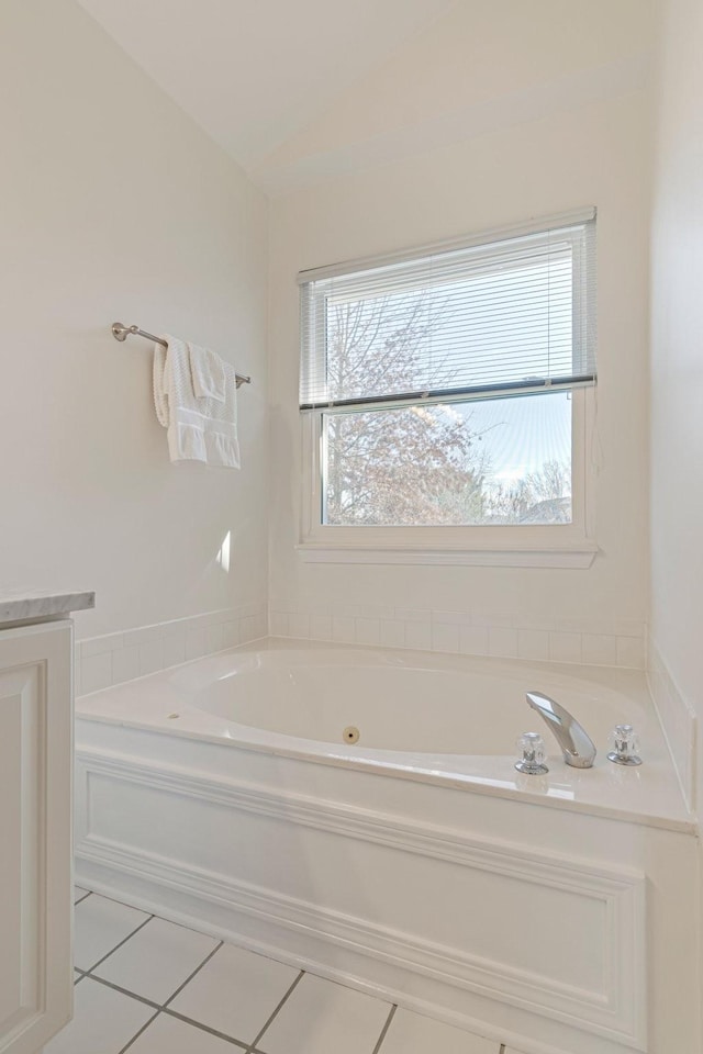 bathroom featuring a tub with jets, vaulted ceiling, and tile patterned floors