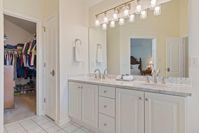 full bath featuring tile patterned flooring, connected bathroom, a sink, a spacious closet, and double vanity