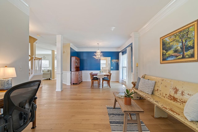 living area featuring crown molding, light wood-style flooring, wainscoting, a chandelier, and stairs