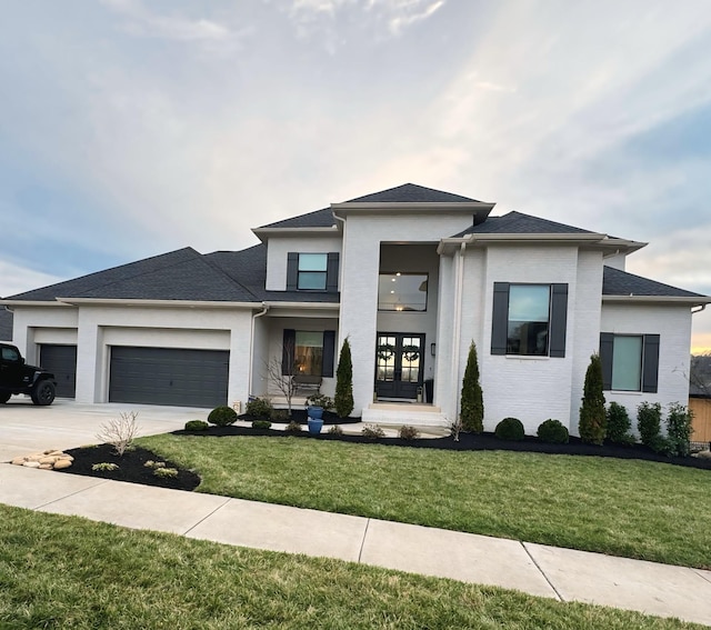 prairie-style home with a garage, driveway, french doors, and a front yard