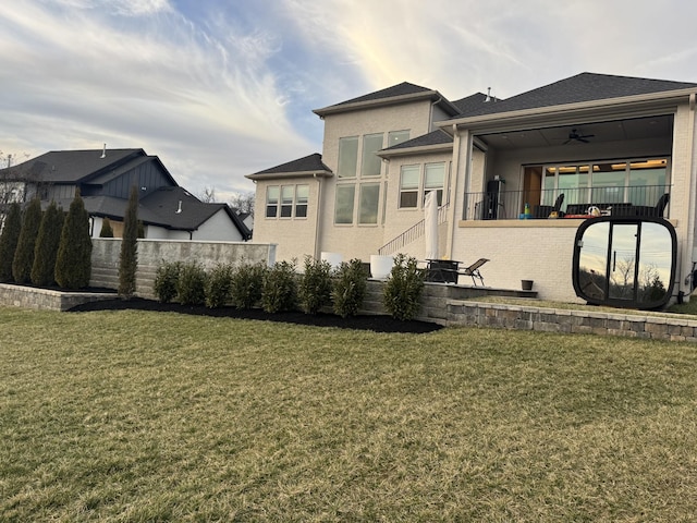 back of property with a ceiling fan, fence, a lawn, and stucco siding