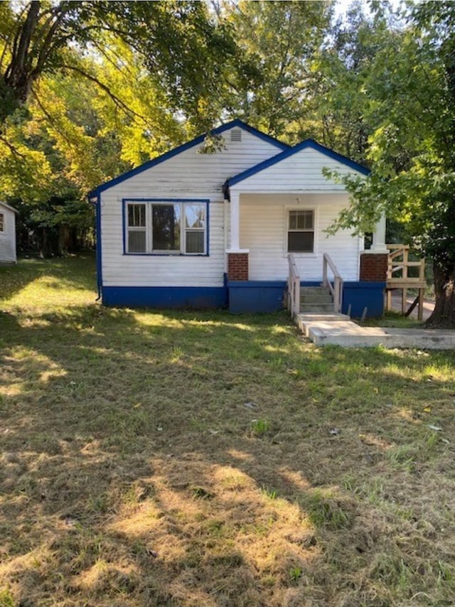 back of property featuring covered porch and a lawn