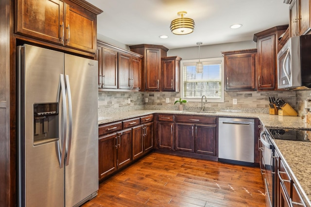 kitchen featuring decorative backsplash, light stone counters, appliances with stainless steel finishes, dark wood-style flooring, and a sink