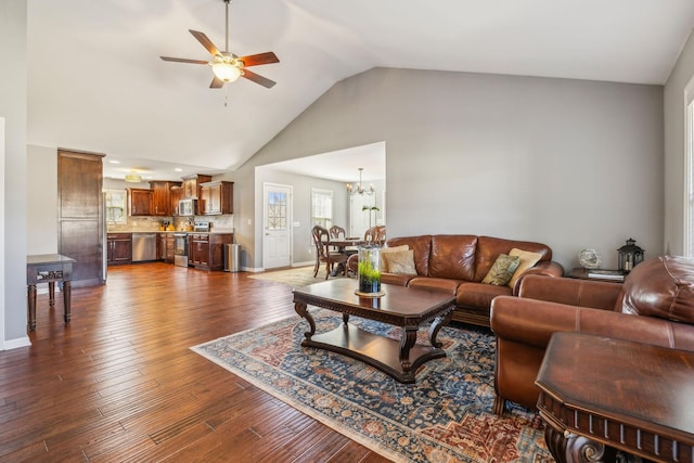 living area with high vaulted ceiling, baseboards, dark wood-type flooring, and ceiling fan with notable chandelier