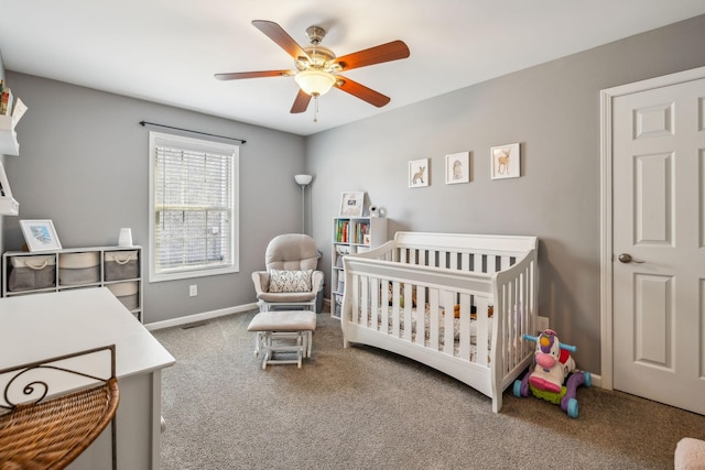 carpeted bedroom with ceiling fan, a crib, visible vents, and baseboards