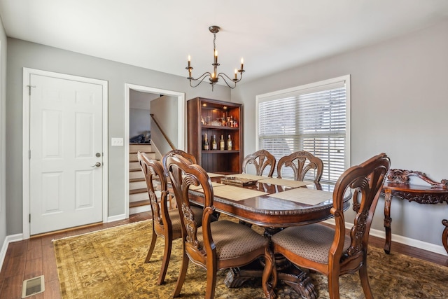 dining space featuring visible vents, stairway, an inviting chandelier, wood finished floors, and baseboards