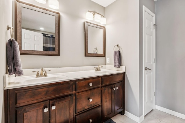 bathroom with double vanity, baseboards, and a sink