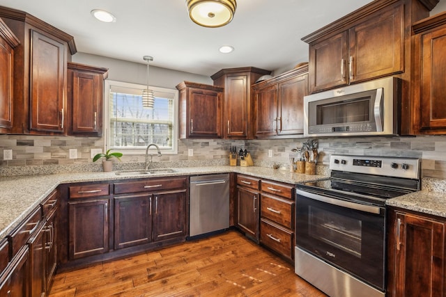 kitchen featuring stainless steel appliances, dark wood-type flooring, a sink, and decorative backsplash